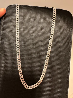 Kedjehalsband i äkta silver 925 - Snyggt halsband med platt kedjedesign i äkta 925 silver. Kedjan har en klassisk, stilren look med blanka länkar som reflekterar ljuset. Perfekt för dig som gillar minimalistiska och tidlösa smycken. Märkt med 925-stämpel för äkthet.