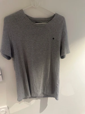 Grå t-shirt från Morris  - Snygg grå t-shirt från Morris Stockholm i storlek M. Klassisk rund hals och korta ärmar. Diskret Morris-logga broderad på bröstet. Mjuk och skön bomullskvalitet som passar perfekt till jeans eller shorts.