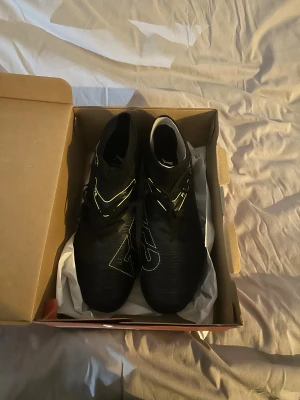 Puma Future 8 Match fotbollsskor dam - Hej!! Jag säljer ett par helt oanvända svarta Puma Future 8 Match FG/AG fotbollsskor i dammodell, med ljusgröna detaljer och snörning. Skorna har stickad strumpkrage för skön passform och är designade för både konstgräs och naturgräs. Om du har minsta fundering är det bara att skriva eller om du vill se fler bilder