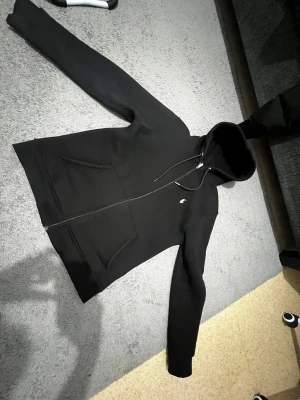 Svart hoodie från Polo Ralph Lauren - Svart hoodie från Polo Ralph Lauren med klassisk vit logga på bröstet. Tröjan har huva med snörning, dragkedja framtill och två stora fickor. Materialet är mjukt och känns som bomull och polyester. Perfekt för chill dagar och streetwear-stil. Pris kan du diskuteras.