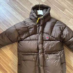  Fjällräven Expedition Pufferjacket - Säljer en brun pufferjacka från Fjällräven. Den är i utmärkt skick och använd sparsamt under förra vinter säsongen!✨(Står xxs men passar min tjej som har s)