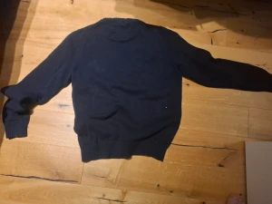 Mörkblå stickad tröja Morris - Snygg mörkblå stickad tröja från Morris med vit logga på bröstet. Tröjan har rund hals, ribbade muddar vid ärmslut och nederkant samt långärmad passform. Perfekt för dig som gillar klassisk stil med en modern touch.