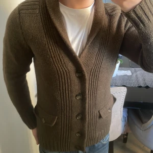 Brun/grön stickad cardigan - Otroligt fet grön/brun stickad cardigan. Modellen är 180cm, 73kg. Priset kan diskuteras.