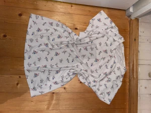 Vit blommig t skjorta  - Supersöt vit t skjorta  med små blommor i blått och rött över hela tyget. T skjortan  har rund hals och korta ärmar, perfekt för varma dagar. Materialet känns mjukt och lätt, troligen bomull. Enkel och fräsch design som ger sommarkänsla. Jätte söt ❤️