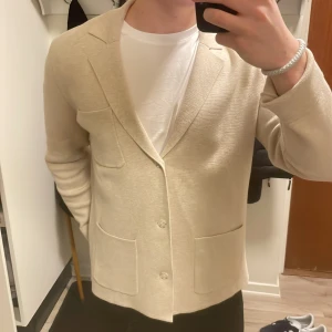 Beige stickad cardigan - Otroligt fin beige stickad cardigan från bläck i toppskick. Modellen är 180cm, 73kg. Priset kan såklart diskuteras.