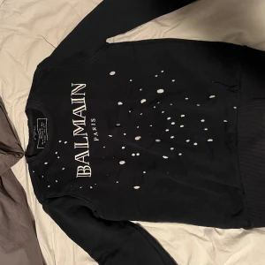 Balmain tjocktröja  - Säljer min balmain tjocktröja för att jag inte har använt den alls många gånger och nu har den blivit för liten. Skick 10/10. Lappen där uppe är lite trasig men abslout ingeting som stör användningen av tröjan. En oroligt fin och skön tröja. 
