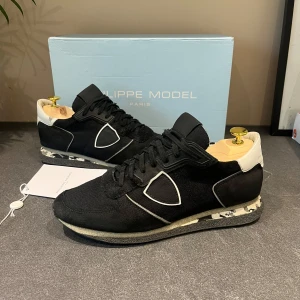 Philippe Model svarta sneakers - Super snugga svarta Philippe Model sneakers med vit detalj. Myxket bra skick 8/10 finns två små defekter där uppe på skon men som inte syns så mycket. Stor 41 storlek passar 42. Sitter väldigt skönt på foten och perfekt till höst och vinter. Box och kort medföljer. 