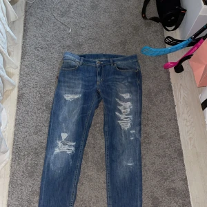 Dondup jeans✌🏼 - Säljer ett par blå dondup jeans med snygga slitningar och distressed detaljer på benen. Jeansen har klassisk femficksdesign, låg till normal midja och är tillverkade i stretchig bomull för skön passform. Perfekta för en avslappnad och trendig look. Obs fickorna är små✌🏼
