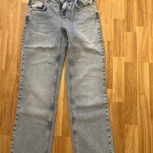 Blå raka jeans från Stradivarius - Säljer ett par klassiska blå jeans från Stradivarius i rak modell. Jeansen har fem fickor, dragkedja och knapp framtill samt snygga kontrastsömmar. Perfekt tvättad denim med en avslappnad vibe och normal passform.