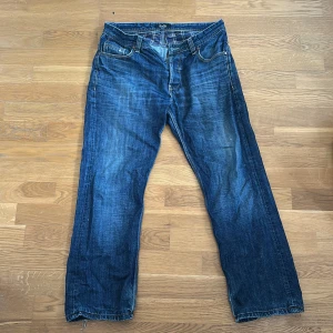  Vintage D&G jeans  - Snygga blå jeans från Dolce & Gabbana med klassisk femficksdesign och raka ben. Jeansen har slitna detaljer vid benslut och en metallpatch med D&G-logga bak i midjan. Tillverkade i robust denim med kontrastsömmar och normal passform.
