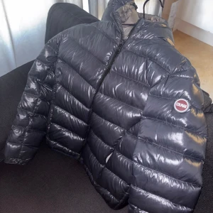 Mörkblå Colmar dunjacka - Snygg, mörkblå COLMAR pufferjavka med huva. Perfekt för vintern. Varm och bekväm, med plats för en tjocktröja under. Storleken är flexibel och passar allt från XS till M. 