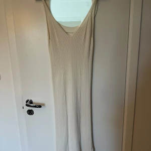 Vit ribbad långklänning LeGer - Supersnygg vit ribbad långklänning från LeGer by Lena Gercke. Klänningen har v-ringning och är ärmlös med en figurnära passform. Perfekt för sommarens alla tillfällen och enkel att styla med accessoarer.