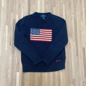Mörkblå stickad tröja Polo Ralph Lauren - Hejsan! Jag säljer min USA tröja från Ralph Lauren i storlek 10-12 år. Den säljs pga av att den är för liten på mig, men är i otroligt bra skick. Den finns nästan inget som tyder på användning och är i precis lika bra skick som att köpa en ny. Den är köpt på Ralph Laurens hemsida för 2.095,00 kr. Den har QR kod för att bekräfta att den är äkta. Skriv om du har några frågor!😁    