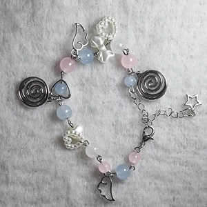 Pastelligt armband med pärlor och berlocker - Superfint armband med pastellrosa, blå och vita pärlor, dekorerat med silvriga spiraler, stjärna, hjärtan, änglavingar och rosett. Flera detaljer i pärlemor och metall ger ett lekfullt och unikt uttryck. Perfekt för dig som gillar söta accessoarer med mycket detaljer.