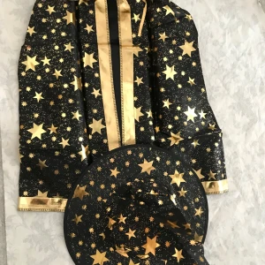 Barn Halloween Cloak med Hatt med guldstjärnor - Cool svart trollkarlshatt med stora och små guldstjärnor över hela hatten. Hatten har en klassisk spetsig form och är perfekt för att sticka ut på maskerad eller temafest. Materialet är glansigt och lätt, vilket gör den bekväm att bära. 