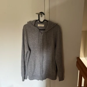 Grå kashmirhoodie från Sayless, M - Mjuk och lyxig grå hoodie från Sayless i 100% kashmir. Tröjan har dragkedja framtill, huva och långa ärmar. Perfekt för dig som vill ha en stilren och bekväm look med premiumkänsla. Snyggt minimalistisk design och riktigt skön passform.använd 2 gånger typ 