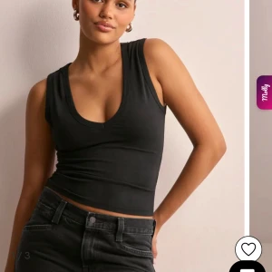 Svart croppad linnetopp med v-ringning - Säljer en svart croppad linnetopp med djup v-ringning och breda axelband. Toppen är figurnära och tillverkad i mjuk bomull, perfekt att styla med jeans eller kjol. Enkel och stilren design som passar till många olika looks.