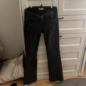 Svarta bootcut jeans från Perfect Jeans - Snygga svarta jeans från Perfect Jeans i storlek 34. Modellen har bootcut-ben och coola bakfickor med lock och knapp.