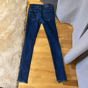 Blå jeans från Tiger of Sweden - Snygga blå jeans från Tiger of Sweden med klassisk femficksdesign och mörkblå tvätt. Jeansen har smal passform och normal midja, perfekta för en stilren look. Tillverkade i mjukt och stretchigt bomullsmaterial för extra komfort.