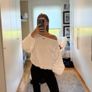 Vit offshoulder blus med ballongärm - Säljer en vit blus med offshoulder-skärning och stora ballongärmar. Blusen har en lös passform och är tillverkad i ett lätt bomullstyg. 