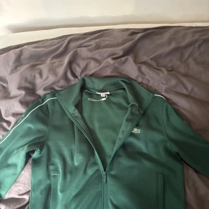 Grön ziptröja från Lacoste - Säljer en riktigt snygg Lacoste tröja , tröjan köptes i Frankrike och använts väldigt få gånger då det inte är min stil