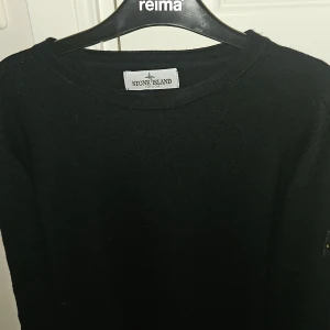 Mörkblå stickad tröja Stone Island Junior - Mörkblå stickad tröja från Stone Island Junior med klassisk rund hals och ikonisk logga på ärmen. Tröjan har lång ärm och är tillverkad i mjukt material som passar perfekt till höst och vinter. Enkel och stilren design som funkar till allt.