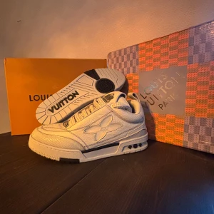 Louis Vuitton skor - Säljer ett par riktigt snygga Louis Vuitton sneakers i vitt skinn med tydlig LV-logga på sidan och coola detaljer på sulan. Skorna har snörning och en chunky sula som ger en modern vibe. Perfekta för dig som vill sticka ut med exklusiva och trendiga sneakers. Allt OG följer med! Snabb affär = billigare pris