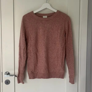 Rosa stickad tröja från Vila - Mysig rosa stickad tröja från Vila med rund halsringning och ribbade muddar vid ärmslut och nederkant. Knappt använd.