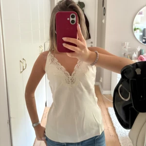 Vit satintopp med spetsdetaljer storlek S - Vit satintopp med spetsdetaljer från Zara i storlek S. Linnet är i mycket bra skick! Perfekt till fest eller till vardags för en clean look! 