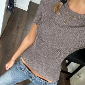 Glittrig ribbad topp  - Supersnygg glittrig topp, ribbad struktur och korta ärmar. Figurnära passform som framhäver siluetten och rund halsringning. Perfekt för dig som vill sticka ut lite extra med en stilren men ändå festlig vibe.
