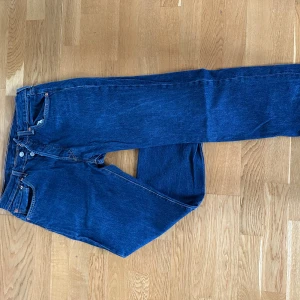 Levi's 501 blå jeans W32 L30 - Klassiska Levi's 501 jeans i en snygg blå tvätt. Rak passform med knappgylf och fyra fickor. Tidlös modell med ikonisk läderpatch bak och röda Levi's-tag på bakfickan. Perfekta till sneakers eller boots.