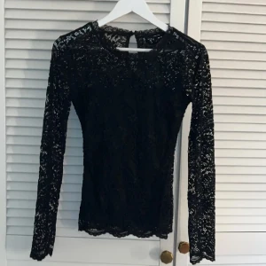 Svart spetsblus från Vero Moda - Supersnygg svart spetsblus från Vero Moda med långärmad design och rund halsringning. Storlek M 