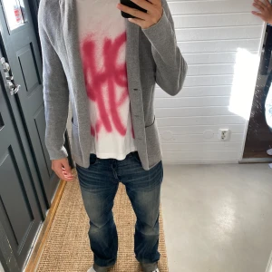 Grå stickad cardigan - Skit snygg ljusgrå stickad cardigan i storlek M, Jag är 182 väger 72 kg. Den saknar två knappar men är skit snygg ändå.