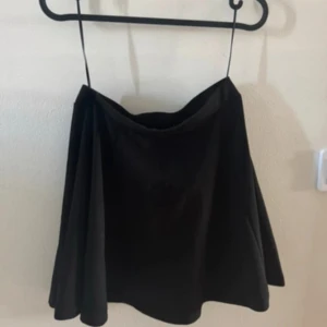 Svart kortkjol i mjukt tyg - Enkel och stilren svart kortkjol med lätt utsvängd form. Kjolen har en slät midja och är sydd i ett mjukt, följsamt material som ger ett snyggt fall. Perfekt att matcha med en cool topp eller stickad tröja. I storlek 36, aldrig använd🤍