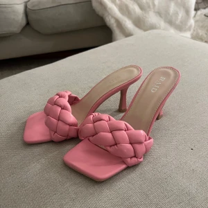 Rosa flätade klackar från RAID - Säljer ett par trendiga rosa klackar från RAID med flätad rem över foten och fyrkantig tå. Skorna har en smal klack och är tillverkade i syntetmaterial. Aldrig använda🌸