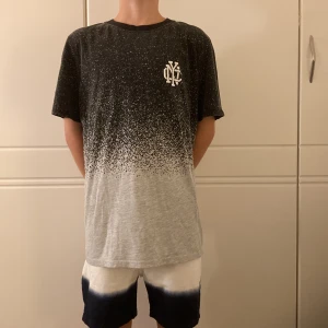 Svart och grå t-shirt från H&M - Cool t-shirt från H&M i svart och grått med fade-effekt och små vita prickar. Tryckt emblem på bröstet. Aldrig använd. 