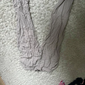 Beige mjukisbyxor med snörning - Säljer ett par beige mjukisbyxor med resår och snörning i midjan. Byxorna har en avslappnad passform och är perfekta för chill dagar. Tillverkade i mjukt material för extra komfort.