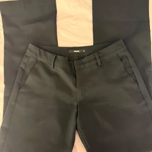 lågmidjade svarta kostymbyxor från BikBok - Svarta kostymbyxor från BikBok med klassisk rak passform. Byxorna har hällor för bälte, snedställda fickor fram och dekorativa fickor bak. Snygg och stilren look som funkar till många olika outfits.