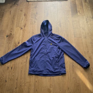Mörkblå Lyle Scott Jacka - Säljer denna riktigt snygga Lyle Scott vindjackan. Den är i ett utmärkt skick och inga synliga defekter. Dragkedjan har tappat en grej som ska sitta på den och där av priset. Annars helt felfri och inga defekter. Perfekt lite tunnare jacka.