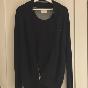 Marinblå kofta från GANT med dragkedja - Snygg marinblå kofta från GANT med dragkedja framtill och diskret logga på bröstet. Klassisk modell med lång ärm och ribbade muddar. Perfekt för lager-på-lager och passar till det mesta. Materialet är mjukt och känns lyxigt. Aldrig använd pågrund av att den var för stor