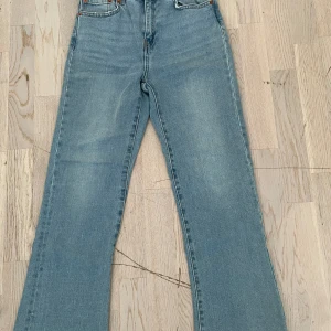 Blå bootcut jeans XS - Snygga ljusblå bootcut jeans i klassisk denim med fem fickor och dragkedja. Jeansen har en rak passform upptill och utsvängda ben, vilket ger en retroinspirerad look. Perfekta för dig som gillar en avslappnad men trendig stil.