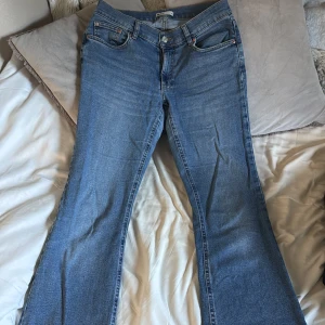 Blå bootcut jeans från Gina tricot  - Snygga blå jeans från Gina tricot med klassisk bootcut-passform. Jeansen är lågmidjande och är tillverkade i mjukt denimtyg. Perfekta för dig som gillar en look med utsvängda ben.