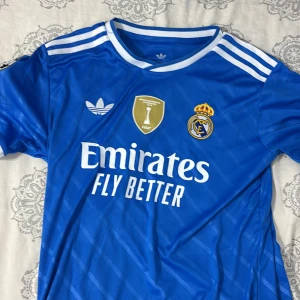 Real madrid 25/26 - Säljer denna real madrid tröja köpt från Unisport.se använd 1 gång (vid test) men den var för stor på mig, fick ingen erbjudan om att lämna tillbaka den och tänkte då att jag säljer den, kan tänka mig byta med något. Frågor? Tveka inte att höra av dig💙. Kan tänka mig gå ner i pris