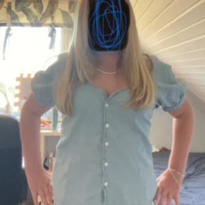 Ljusblå jeans blus från Levi's - Superfin ljusblå jeans blus från Levi's med korta puffärmar och v-ringning. Blus har knappar hela vägen framtill och är i klassisk denim. Perfekt för dig som gillar en avslappnad men ändå söt stil.