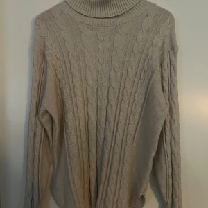 Beige polotröja Claura från Freequent - Säljer en beige polotröja från Freequent i storlek L. Tröjan är stickad med klassiskt flätmönster, har hög polokrage och långa ärmar. Perfekt för kyliga dagar och superenkel att styla med jeans eller kjol. Mjuk och skön, knappt använd 