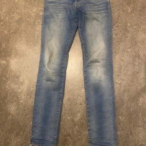 Slim fit jeans från Jack & Jones - Snygga blå slim fit jeans från Jack & Jones, modell Glenn. Jeansen har klassisk femficksdesign, normal midja och är tillverkade i mjukt denimtyg. Perfekt passform med smalare ben och diskret slitning framtill för en modern look.