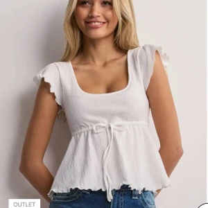 Vit blus  Nelly - Supersöt vit blus från Nelly i storlek s, med volangärmar och knytband i midjan. Toppen har en lätt rynkad struktur, rundad halsringning och vågig kant nertill. Skriv om ni har några frågor🤍🤍