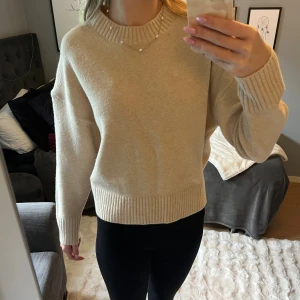 Beige stickad tröja - Supermjuk beige stickad tröja från Zara i storlek XS. Tröjan har ribbade muddar vid ärmslut, nederkant och halsringning. Den har en rak, lite loose passform och är perfekt för lager-på-lager under höst och vinter.
