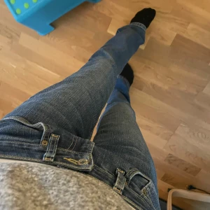 Levi's lågmidjade bootcut jeans blå denim - Säljer ett par klassiska blå lågmdiajde Levi's jeans i bootcut-modell. Jeansen har normal passform, fem fickor och snygga kontrastsömmar. Tillverkade i slitstark denim med en autentisk blå tvätt. Perfekta för dig som gillar en tidlös och avslappnad stil. Innerbenslängd 79cm, midjemått 39,5cm