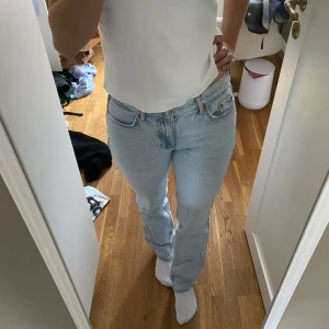 Ljusblå jeans straight fit - Säljer ett par klassiska ljusblå jeans med rak passform och normal midja. Jeansen har fem fickor, knappgylf och är tillverkade i 100% bomull. Perfekta för en avslappnad och tidlös stil.
